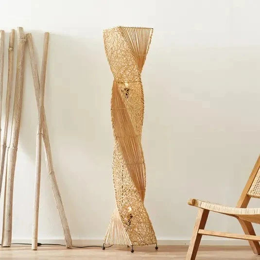Lampadaire sur pied rotin design torsadé présenté près de bambous et d'une chaise