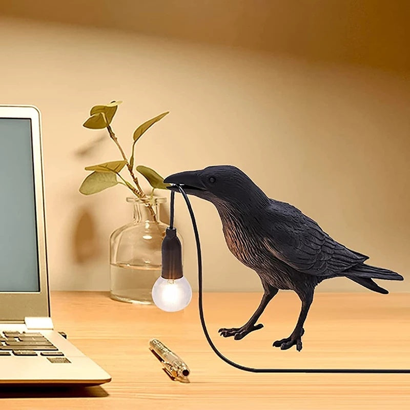 Lampe corbeau avec lumière dans son bec design et originale présente sur un bureau près d'un ordinateur