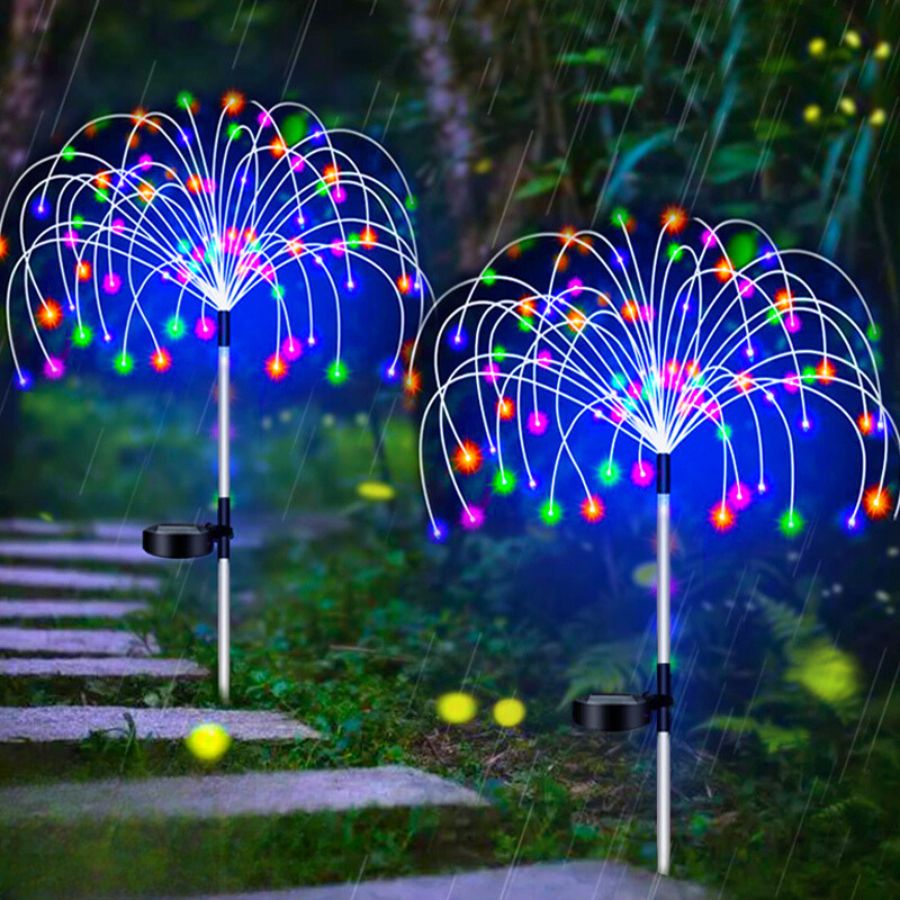 Deux lampes solaires en formes de feux d'artifices multicolores plantées dans une allée de jardin.